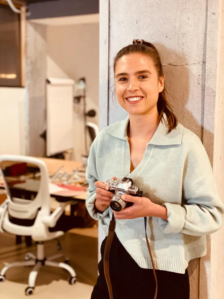 Fotógrafa en coworking Málaga Fotógrafa sonriente con cámara en un espacio de coworking en Málaga