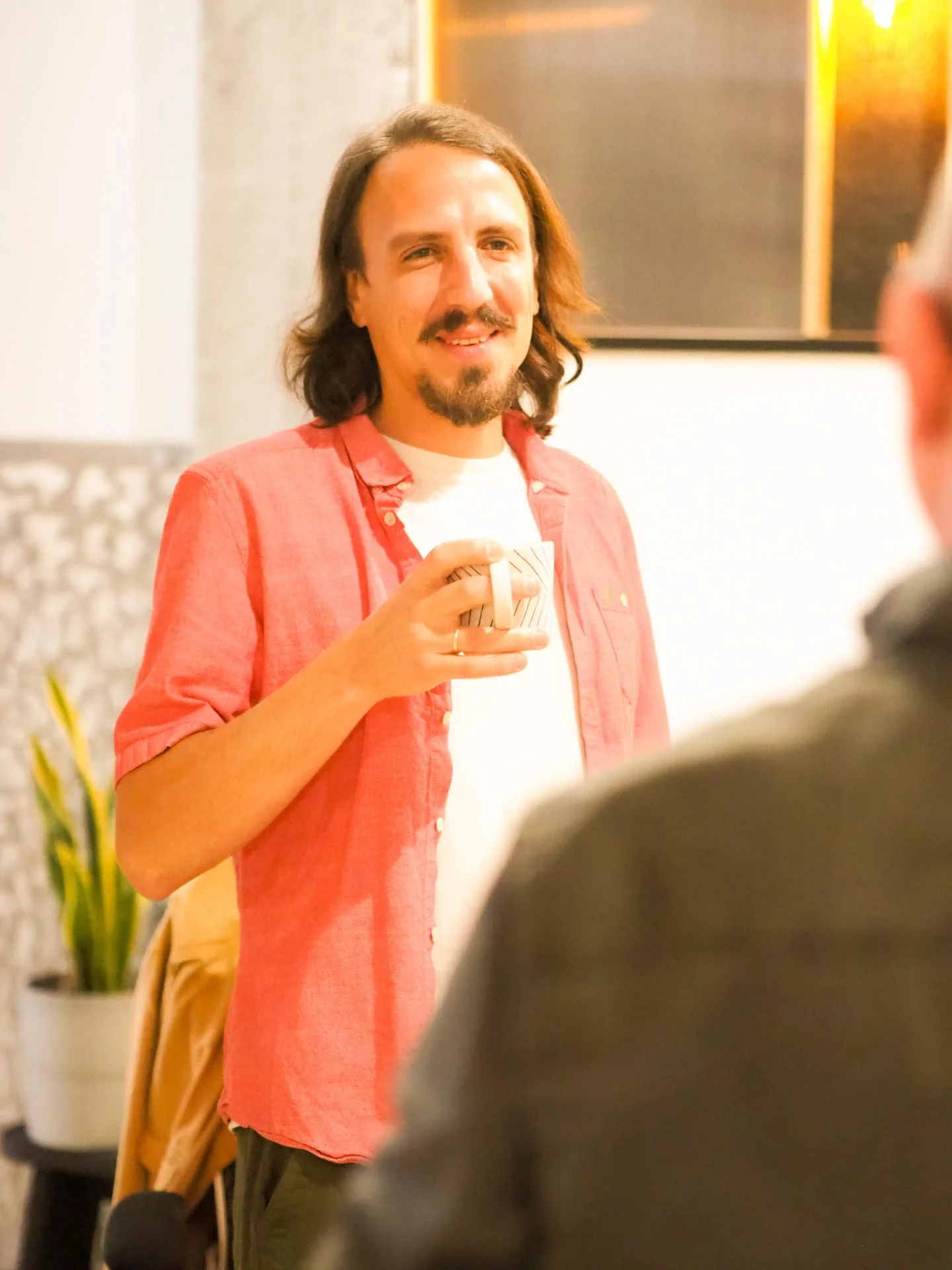 Hombre sonriendo mientras disfruta un café en un espacio de coworking