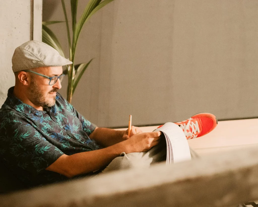 Hombre tomando notas en espacio de trabajo Hombre sentado tomando notas en una libreta en espacio de trabajo