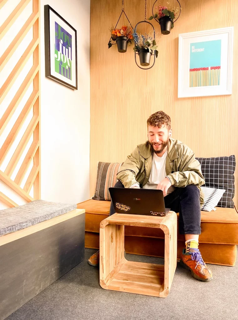 Trabajar con comodidad en un coworking moderno Hombre joven sonriendo mientras trabaja con su portátil en un coworking